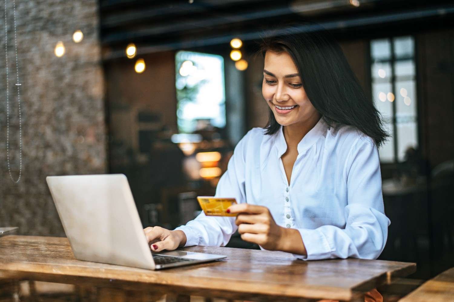 woman sat with laptop in the cafe using credit card to pay with the help of payment gateway