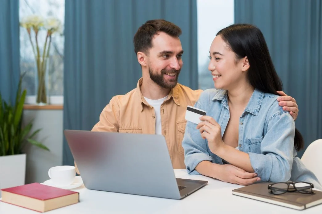 A couple is sitting in front of a laptop with a card.