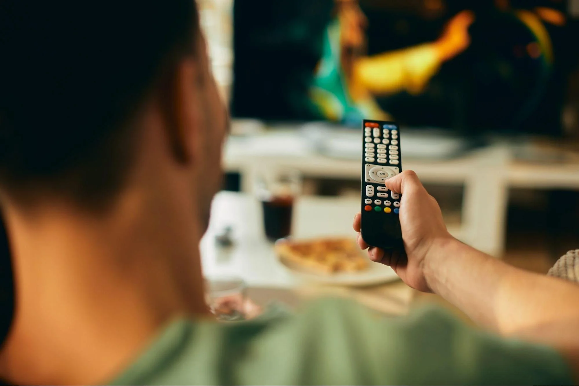 A man is holding an IPTV remote to control his tv
